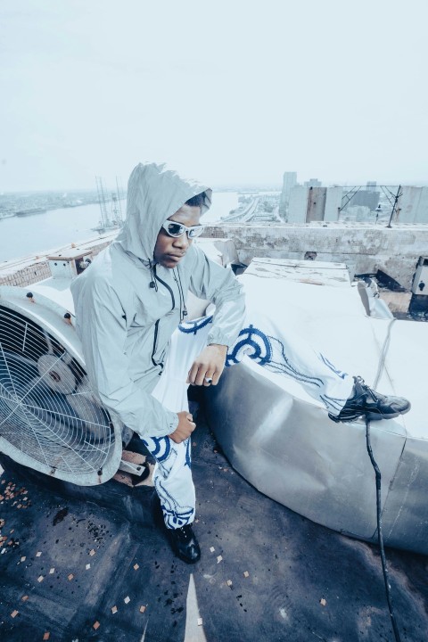 a man sitting on top of a roof next to a fan