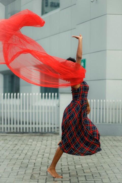 a woman in a dress is holding a red scarf