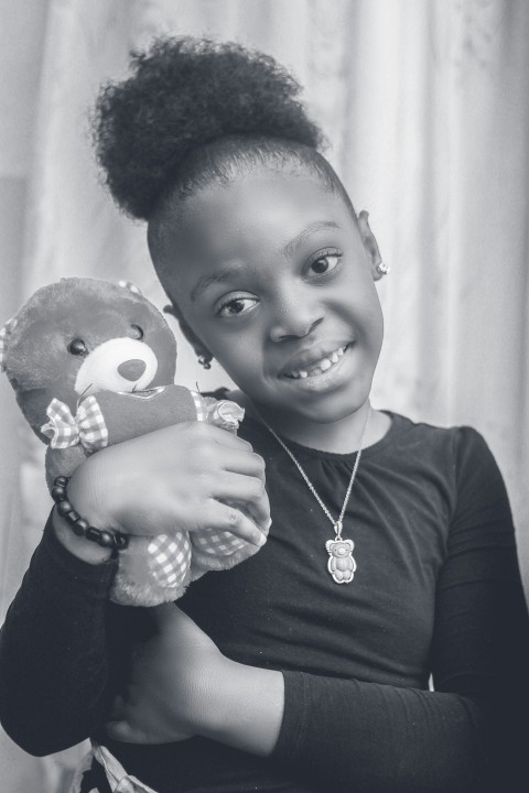 a young girl holding a teddy bear in her arms