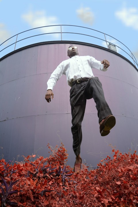 man in white dress shirt jumping over the plant in