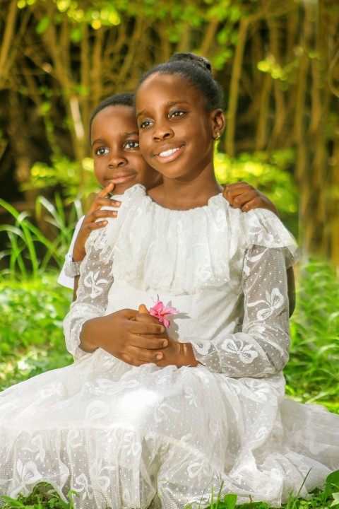 two young girls are sitting in the grass