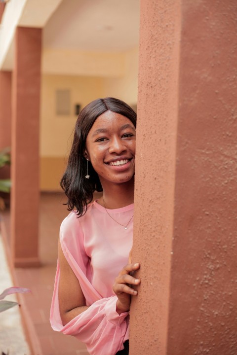 a woman is smiling and leaning against a wall