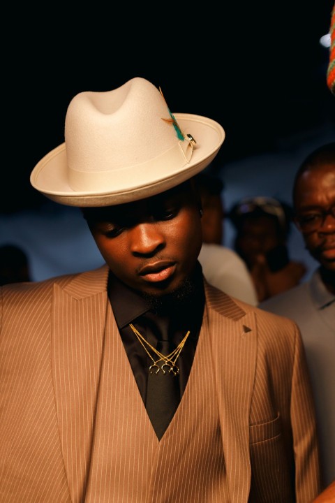 a man wearing a suit and a white hat