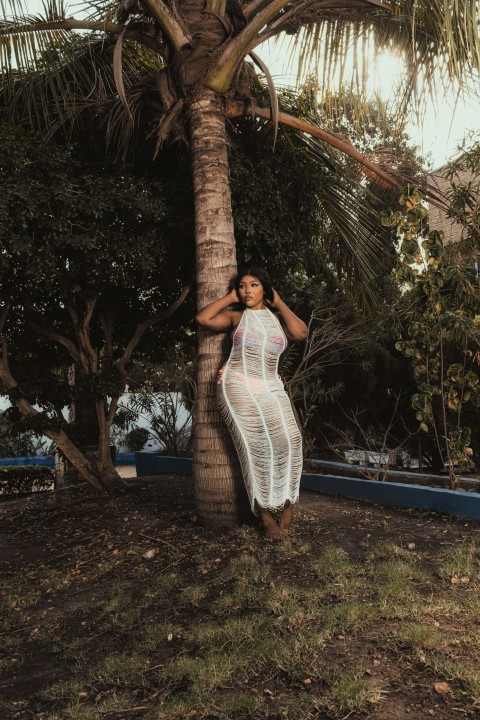 a woman standing next to a palm tree