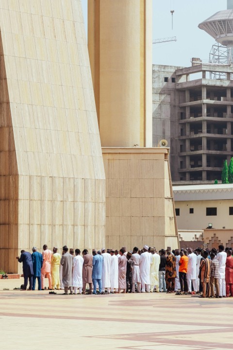 a group of people standing in a line in front of a building Gflc