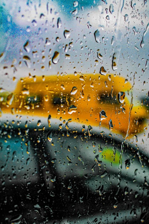 a rain covered window with a school bus in the background