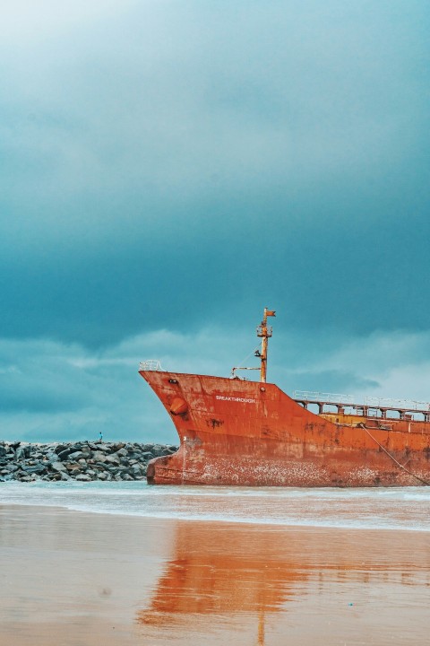 a large rusted ship sitting on top of a sandy beach WUFfkdft