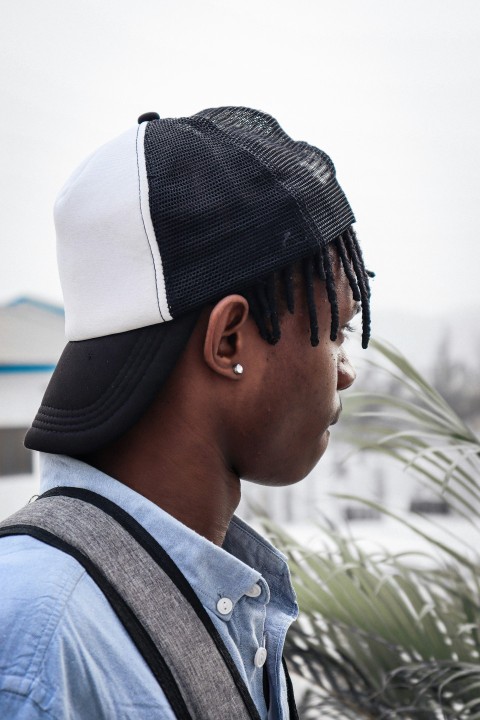 a man with dreadlocks wearing a black and white hat p