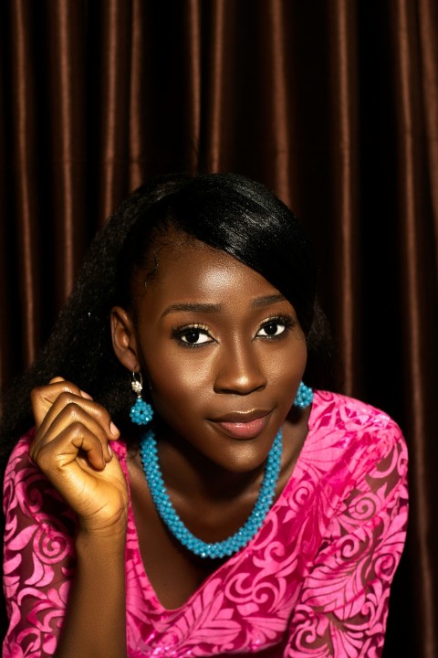 a woman in a pink dress with a blue beaded necklace