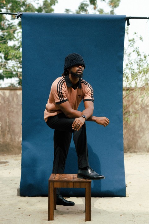 a man sitting on a stool in front of a blue backdrop