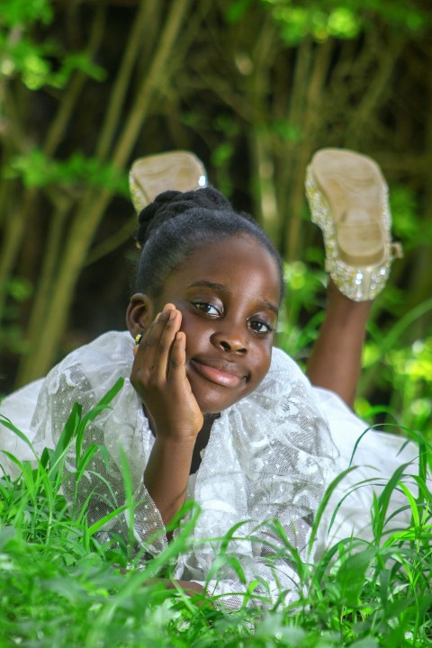 a girl laying in the grass with her hands on her face