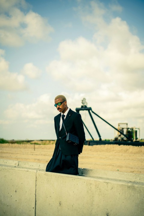 a man in a suit and sunglasses standing on a rooftop