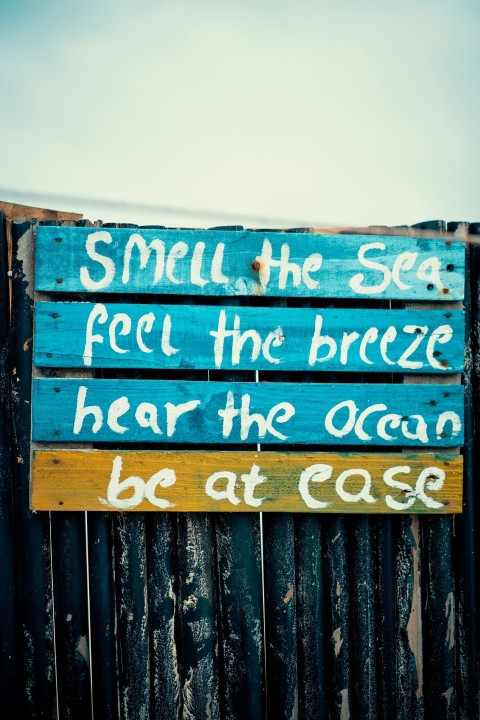 a wooden sign that says smell the sea feel the breeze hear the ocean be at