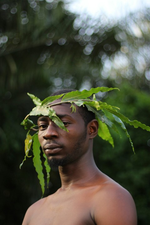 man in white tank top holding green leaves during daytime