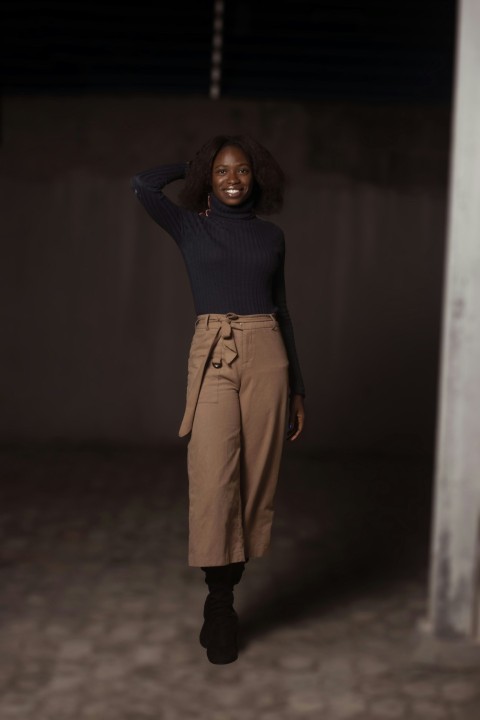 a woman standing in a dark room with her hands on her head