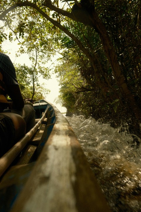 a man riding on the back of a boat down a river Q02Su7Lr