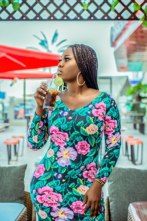 woman in white red and blue floral long sleeve shirt drinking from clear drinking glass