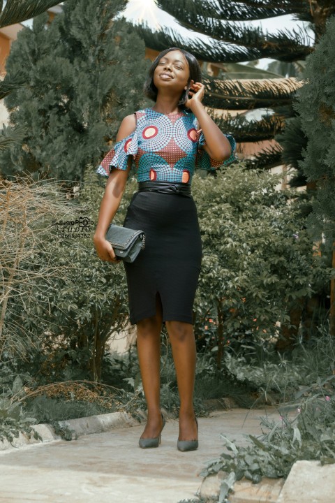 woman in black and white polka dot shirt and black skirt standing near green plants during