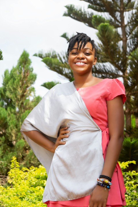 smiling woman in white and red t shirt standing near green trees during daytime