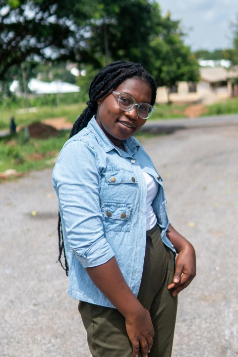 woman in blue denim button up shirt and black shorts standing on road during daytime