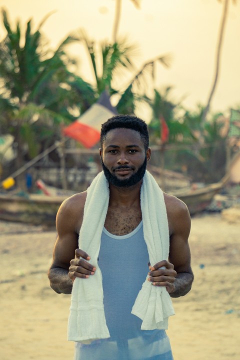 man in white tank top standing on brown sand during daytime
