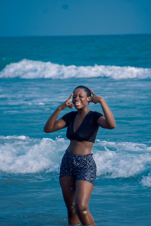 woman in black sports bra and blue and white shorts standing on beach during daytime