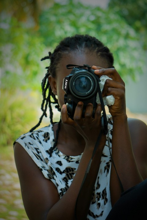 woman in black and white floral tank top holding black nikon dslr camera 2L