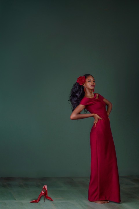 a woman in a red dress standing next to a pair of red shoes