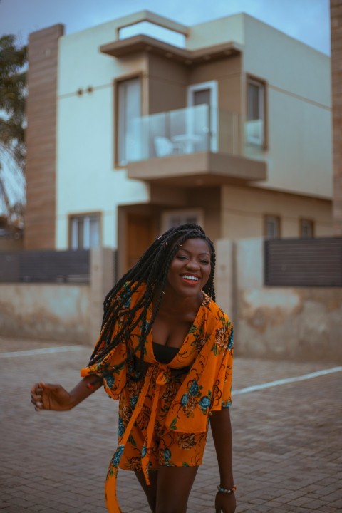 a woman with dreadlocks walking in front of a house