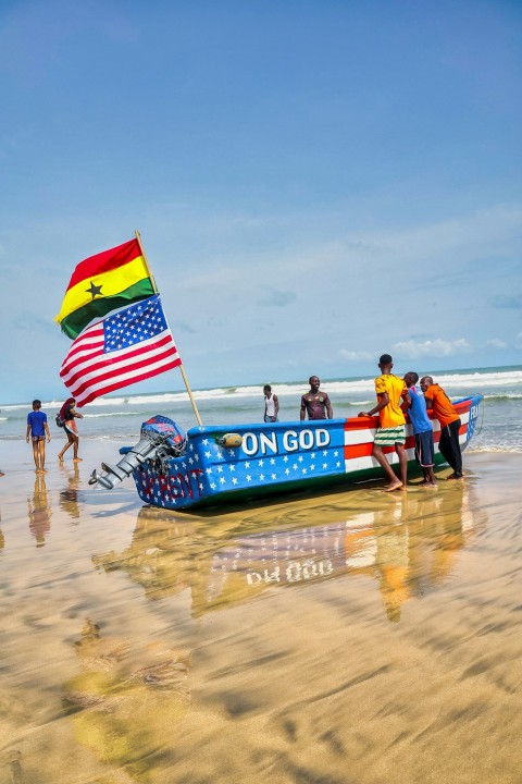 a group of people standing on a beach next to a boat