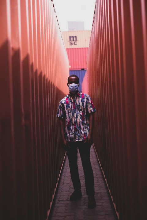 man in black and white floral long sleeve shirt and black pants standing on hallway