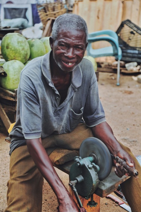 a man sitting on a piece of wood with a grinder uWrOW