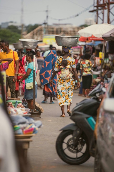 a woman walking down a street with a bucket on her head