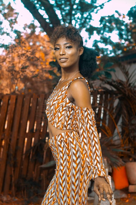 a woman in an orange and white dress posing for a picture