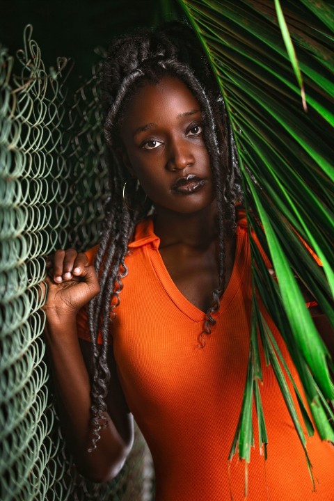 a woman with dreadlocks standing next to a palm tree