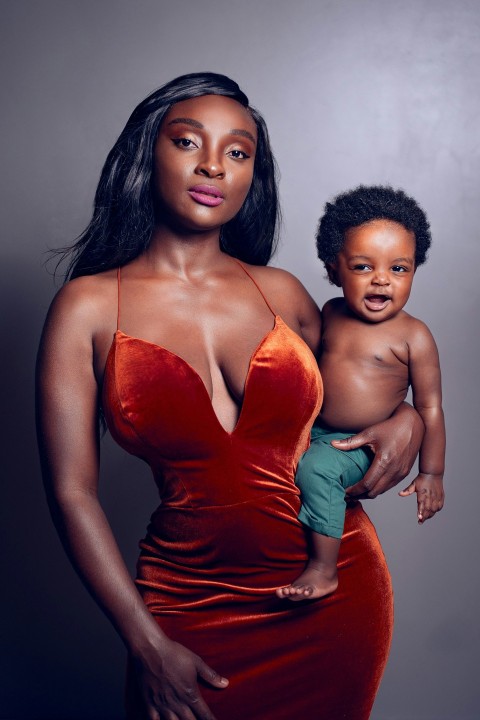 woman in red spaghetti strap dress beside topless boy