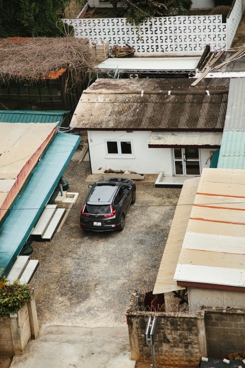 a black car parked in a parking lot next to a house