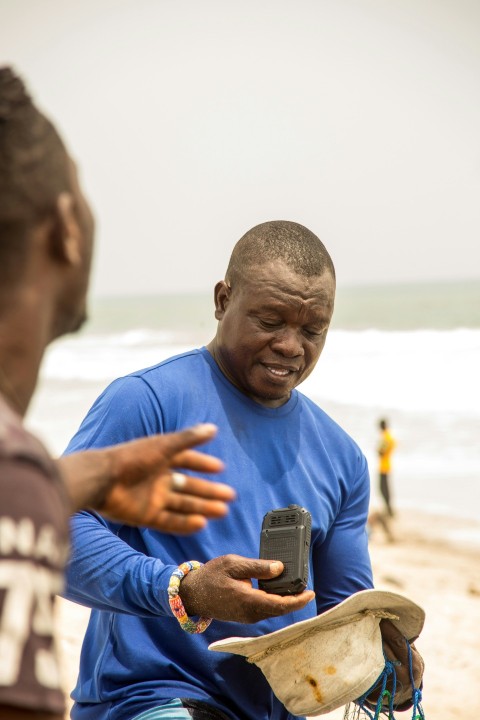 man in blue crew neck t shirt holding black smartphone