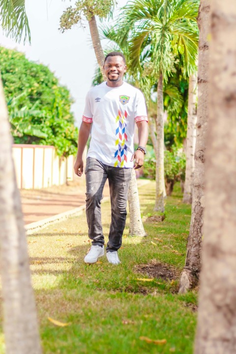 man in white crew neck t shirt and blue denim jeans standing on green grass field