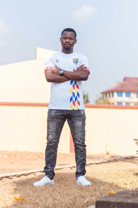 man in white crew neck t shirt and blue denim jeans standing on brown sand during