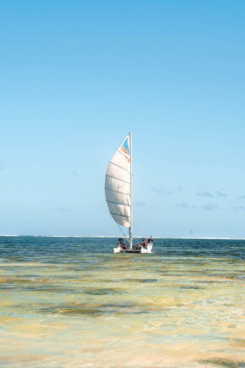 a sailboat with two people on it in the ocean _riRvDikb