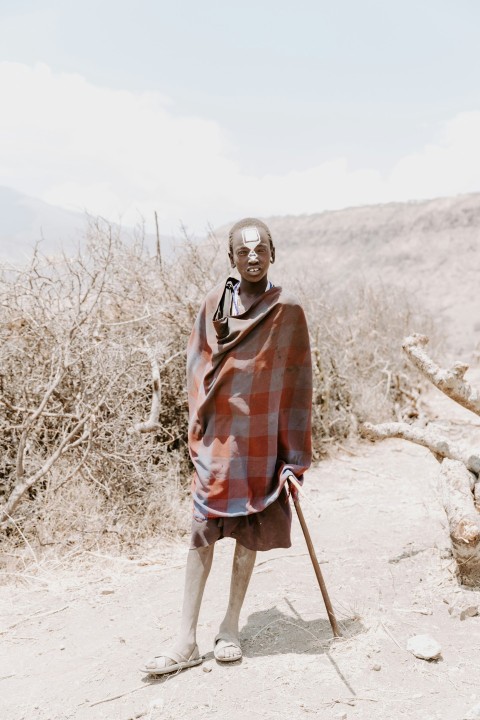 man in red and white plaid dress shirt wearing black sunglasses standing on brown field during