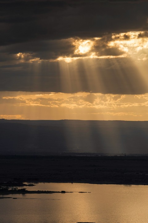 the sun shines through the clouds over a body of water