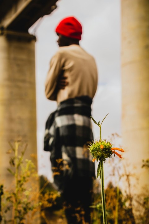 a man standing in front of a bridge with a red hat on