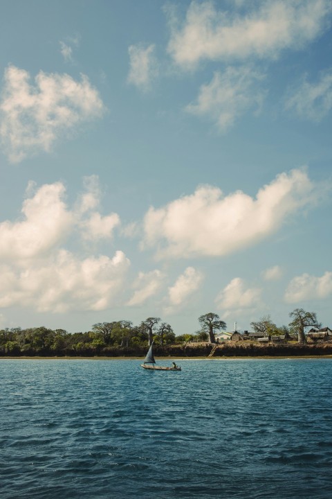 white boat on sea under white clouds and blue sky during daytime