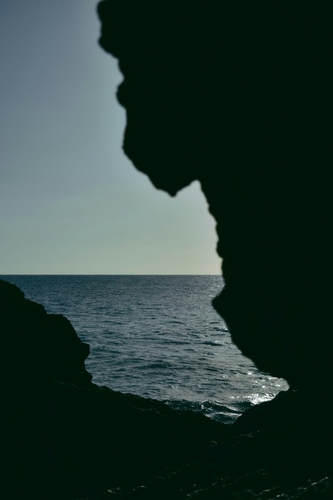 a person standing on a rock near the ocean isIdesK