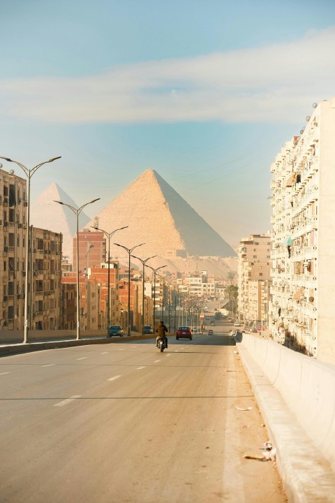 a man riding a motorcycle down a street next to tall buildings