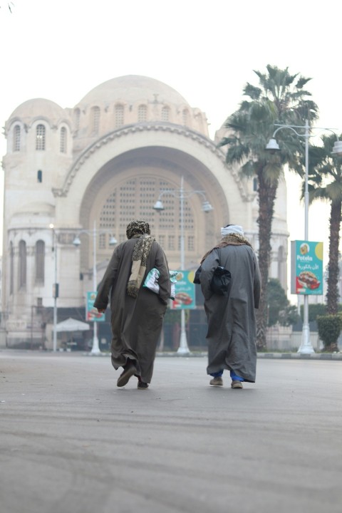 two men walking down a street in front of a building