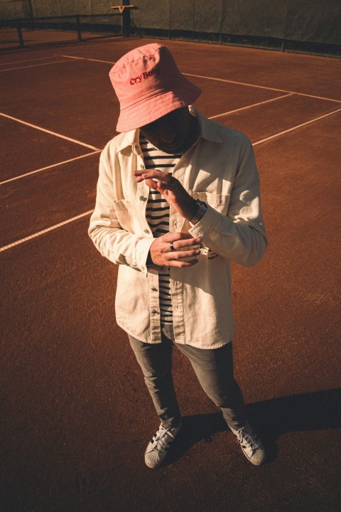 a person wearing a hat and a jacket on a tennis court