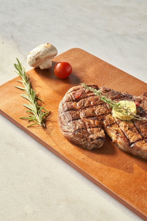 sliced bread with sliced tomato and meat on brown wooden chopping board